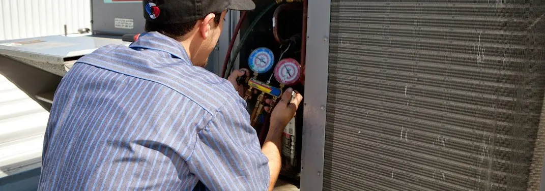 HVAC technician servicing a condenser unit in Forest Park
